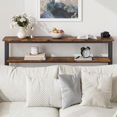 a white couch sitting under a painting on top of a wooden shelf