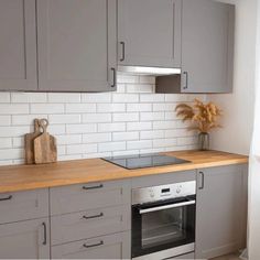 a kitchen with white cabinets and wood counter tops, an oven and stove top in the middle