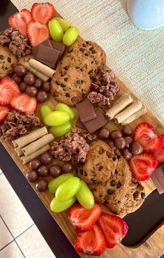 an assortment of cookies, strawberries and chocolate chips on a cutting board