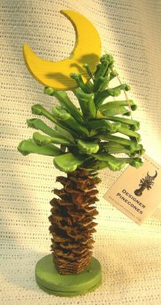 a fake pine cone with green leaves and a yellow crescent on top is sitting on a table