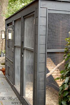 an outdoor chicken coop in the middle of a garden with plants and trees around it