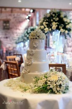 a wedding cake sitting on top of a table covered in white flowers and greenery