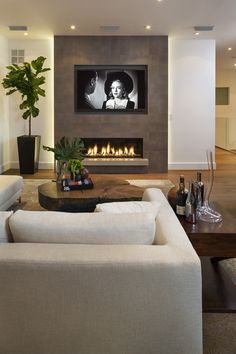 a living room with two white couches and a large television mounted above the fireplace