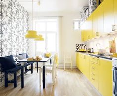 a kitchen with yellow cabinets and black chairs in front of the counter top, next to a dining table