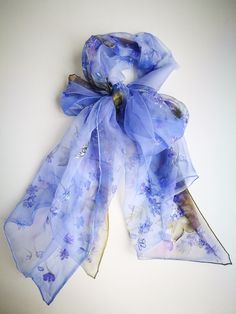 Hand painted charming silk chiffon scarf - Hepatica flowers. Alluring Blue-violet small Spring flowers blossoming all length long of this scarf. Few spring butterflies accompany this nature beauty. In Lithuanian language we call this flower 'Zibuokle'- that who sparkle , twinkle :) Truly these flowers seem shine in early spring on last autumn leaves ground . And So this painting was inspired :) Chiffon is very light and transparent silk fabric. It is transparent in one layer and rich colors are Purple Silk Scarf With Floral Print For Spring, Purple Floral Print Silk Scarf For Spring, Purple Silk Scarves For Spring, Painted Violets, Spring Shawl, Spring Wraps, Blue Blossom, Blue Periwinkle, Short Scarves