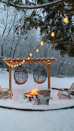 a fire pit surrounded by chairs and lights in the snow