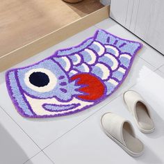 a pair of slippers sitting on the floor next to a fish shaped door mat