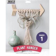 a plant hanger is hanging on the wall next to a vase and other items