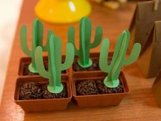 three plastic cactus planters sitting on top of a wooden table next to coffee beans