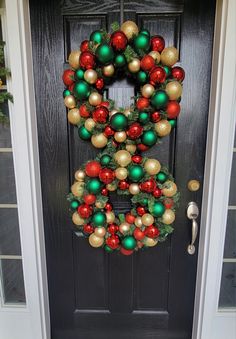 a christmas wreath is hanging on the front door with red, green and gold ornaments