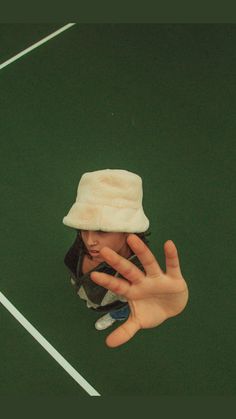 a person wearing a white hat and holding their hand up to the camera