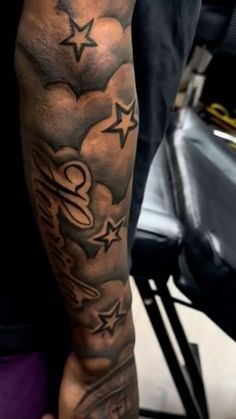 a man's arm with stars and clouds tattooed on the side of his arm