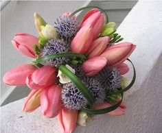 a bouquet of pink flowers sitting on top of a white tablecloth next to a window