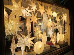 a display case filled with lots of white paper stars and lanterns hanging from it's sides