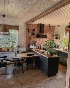 an open kitchen and dining room area with brick walls, wood flooring and exposed ceilings