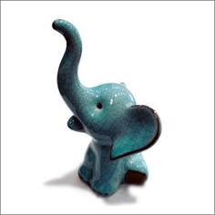 an elephant figurine sitting on top of a white surface