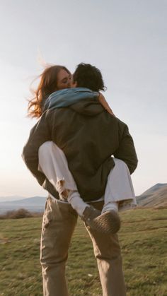 a man and woman hug in the middle of a field