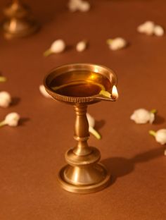 a small metal candle holder sitting on top of a table covered in white flower petals