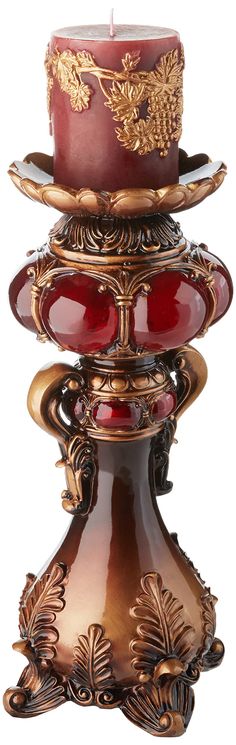 a red candle is sitting on top of an ornate stand with two candles in it