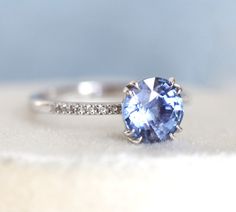 This beautiful ring features 2 - 2.1 ct sparkly blue sapphire. The design can be made with gemstones of your choosing. If you would prefer a custom ring, please contact us before purchase. Details Main stone Gemstone: natural blue sapphire, comes with certificate, ethically sourced 2 - 2.1ct Side stones Gemstone: white diamonds half eternity Quality: clarity grade VS, color grade G, conflict-free Band width: approx 1.8 mm Material: 14/18k solid yellow/white/rose gold, platinum Sizes available: 3 Dazzling Sapphire Round Cut Rings, Dazzling Sapphire Ring With Round Cut, Timeless Sapphire Ring With Round Band, Dazzling Blue Sapphire Ring With Accent Stones, Sapphire Rings With Brilliant Cut, Tanzanite Sapphire Promise Ring With Ethical Diamonds, Promise Sapphire Ring With Center Stone, Dazzling Moissanite Sapphire Ring Round Cut, Ethical Sapphire Fine Jewelry Ring