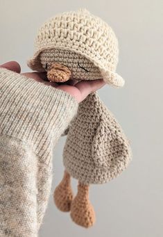 a hand holding a stuffed animal wearing a knitted hat