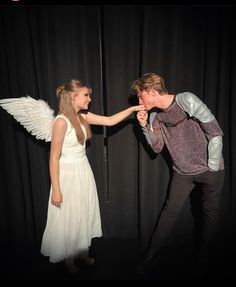 two people standing in front of a curtain with one pointing at the other's hand