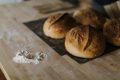 bread rolls sitting on top of a wooden cutting board