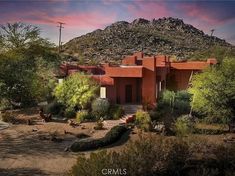 an adobe - style house sits in the middle of a desert landscape with mountains and trees