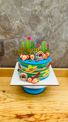 a birthday cake decorated with cactus and succulents sits on a wooden table