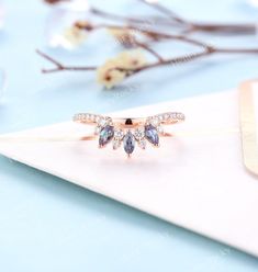 an open ring with three pear shaped blue stones on it, sitting on top of a white envelope