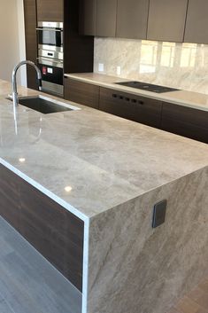 a modern kitchen with marble counter tops and stainless steel appliances