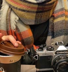 a person holding a coffee cup next to a camera