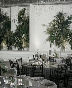 the tables are set up for an event with flowers and greenery on each table