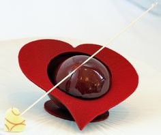 a red heart shaped object sitting on top of a white plate next to a stick