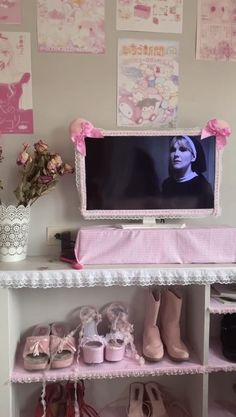 a tv that is on top of a shelf with some shoes in front of it