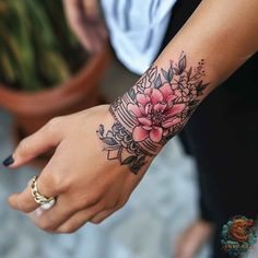 a woman's hand with a flower tattoo on the left wrist and right arm