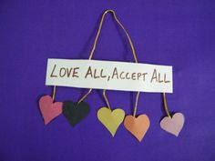 three hearts hanging on a string with a sign that says love all accept all over it