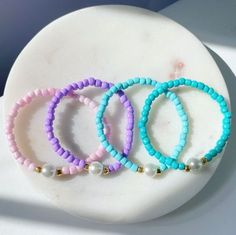 three bracelets with pearls and beads on a white plate