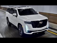 a white suv driving down a street next to a building