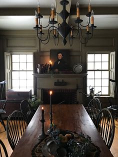 a dining room table with candles on it and a man sitting at the end of the table