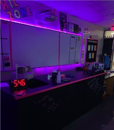 an office with purple lighting and neon writing on the counter top is seen in this image