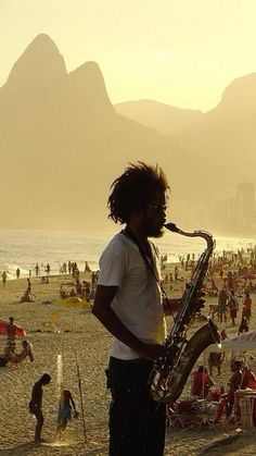 a man standing on top of a beach next to a saxophone