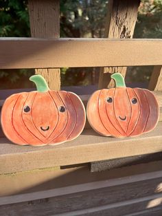 two carved pumpkins sitting on a wooden bench