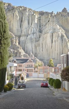 cars parked on the side of a road in front of a large rock mountain range