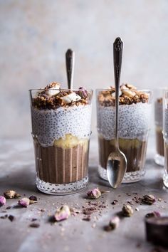 three glasses filled with dessert sitting on top of a table