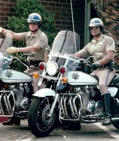 two police officers riding on the back of motorcycles