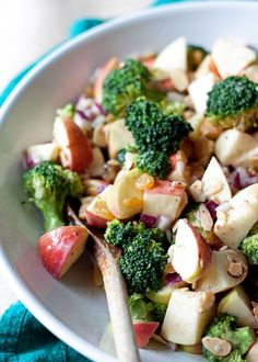 a white bowl filled with broccoli, apples and other vegetables on top of a blue towel