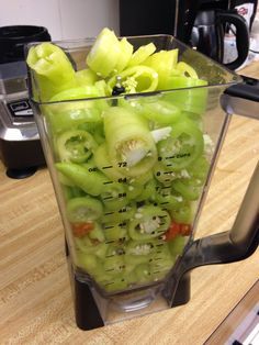 a blender filled with green vegetables on top of a wooden counter