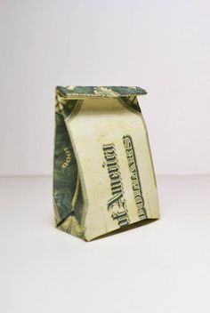 an origami dollar bill folded into a small bag on a white table top