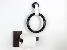 a black and white toilet paper holder with a ring hanging on it's side